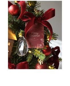 Close-up of velvet bows, star wooden house and baubles hanging on festive Xmas tree
