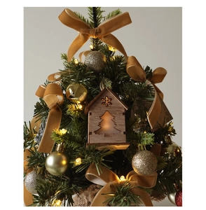 Detail of mini Christmas tree featuring warm LED lights, velvet bows, and golden ornaments