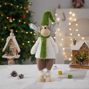 Plush Christmas gnome doll in green hat with reindeer ears and silver wings on festive background