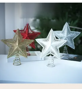 Close-up of glittered Christmas tree toppers in gold, red and silver on a white table