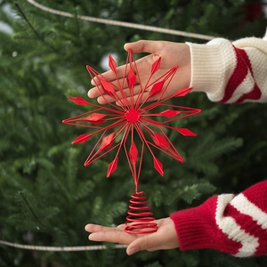 Detailed view of a red metal Christmas tree topper star with spiral base held by hands