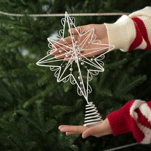 Detailed view of a white wrought iron Christmas star tree topper with silver beads