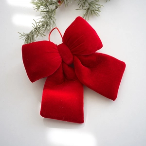 Red velvet bow Christmas ornament with hanging loop on a white festive background