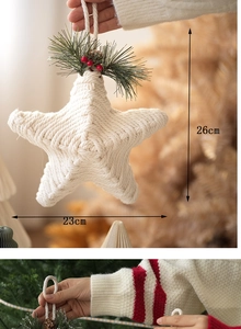 Detail of 26cm handmade white knitted star ornament with pine needles and red berries