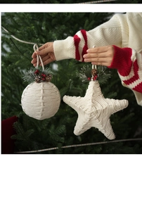 Detail of white rope Christmas ball and star ornaments with pine cones and berries