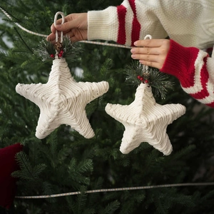 Handmade twine Christmas star ornaments with pine needles and berries on a tree