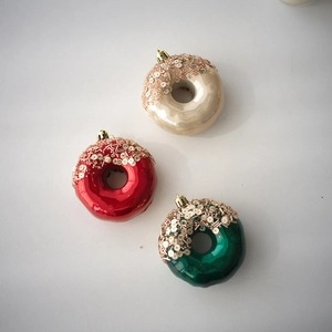 Close-up of shiny doughnut-shaped Christmas ornaments with gold sequins and hangers