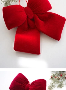 Close-up of red velvet Christmas tree bow decorations with festive pine needle accents