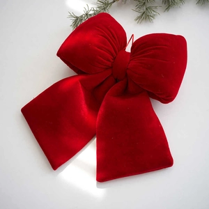 Red velvet Christmas tree bow decoration with festive pine needle on white background