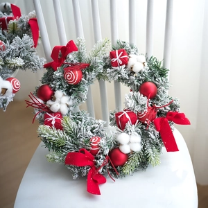 Couronne de Noël 40cm avec aiguilles enneigées, boules rouges et ruban sur chaise blanche