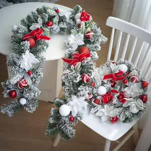 Détail d'un ensemble couronne et guirlande de Noël enneigée de 40 cm avec nœuds rouges