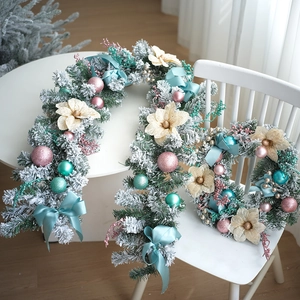 Détail d'une couronne de Noël de 40 cm avec nœuds bleus et ornements roses sur neige
