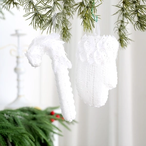 Gros plan de sucres d'orge et de moufles à paillettes blanches sur une branche de sapin