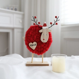 Detail of wool felt Christmas reindeer ornament with XMAS heart and wooden base stand