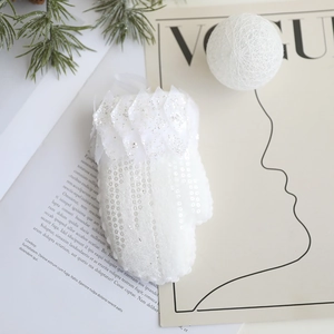 Gros plan d'un gant de Noël blanc à paillettes avec détail de feuilles argentées