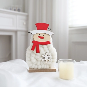 Macro detail of a handmade wool felt snowman ornament with red hat and wooden base