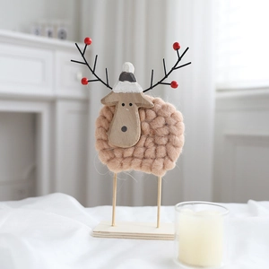Close-up of wool felt sheep Christmas ornament with wooden base and festive antlers