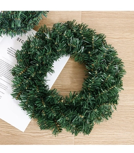 Close-up of green PVC Christmas wreath with realistic pine needles on wood background