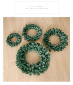 Set of four green artificial PVC pine wreaths in varying sizes on light wood background