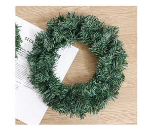 Close-up of artificial green PVC Christmas wreath on a light wood background texture