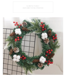 Détail d'une couronne de Noël DIY avec aiguilles de pin, baies rouges et pommes de pin
