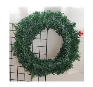 Gros plan d'une couronne de Noël DIY avec des aiguilles de pin et des baies rouges