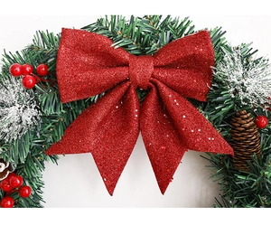 Détail d'une couronne de Noël avec nœud rouge pailleté, pommes de pin et sapin enneigé