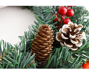 Gros plan d'une couronne de Noël DIY avec pommes de pin, baies rouges et aiguilles de pin