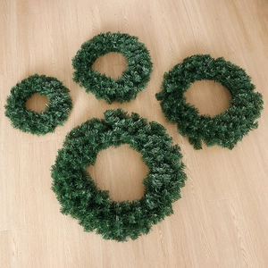 Set of four artificial green PVC Christmas wreaths in varying sizes on a wooden background