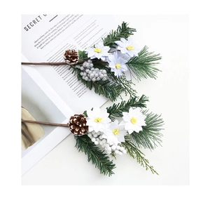 Détail de branches de Noël artificielles avec aiguilles de pin, cônes et baies sur fond blanc