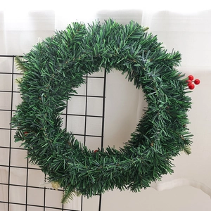 Couronne de Noël avec aiguilles de pin vertes et baies rouges sur une grille noire