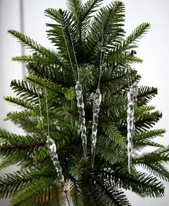 Primer plano de adornos de carámbanos acrílicos transparentes en un árbol de Navidad verde