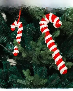 Close-up of red and white striped foam candy cane ornaments hanging on a green Christmas tree
