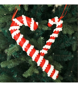 Close-up of red and white glitter candy cane ornaments hanging on a green Christmas tree