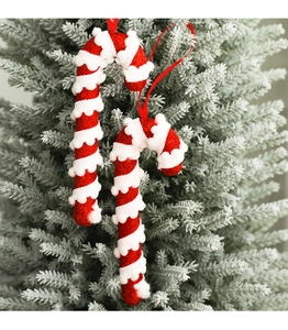 Macro detail of red and white foam candy cane ornaments hanging on a frosted Christmas tree