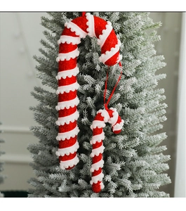 Detail of red and white glitter candy cane ornaments hanging on a snowy Christmas tree