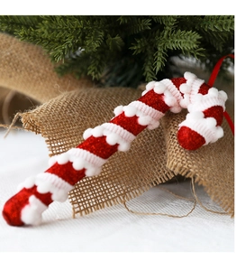 Close-up of red glitter and white plush candy cane ornament on a rustic pine branch