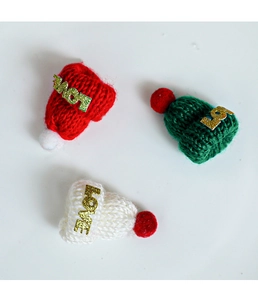 Detail von Mini-Strickmützen in Rot Grün und Weiß mit goldenen LOVE Schriftzug Details