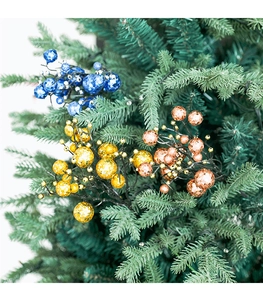 Detail van glinsterende kerstbessen in blauw en goud op groene dennennakken
