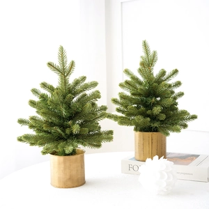 Green artificial Christmas tree in golden metal pot for festive table decoration