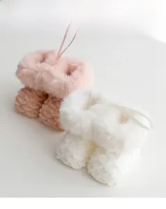 Detail view of pink and white plush knit Christmas boot ornaments with faux fur trim