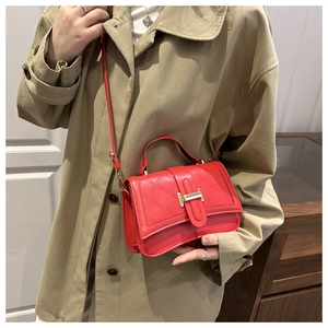Detailed view of red leather crossbody bag with quilted pattern and metal T-clasp