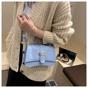 Detail of light blue quilted crossbody bag featuring golden H-shaped clasp and top handle