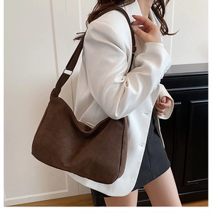 Side view of dark brown suede hobo bag with adjustable silver buckle on a model