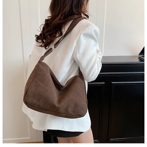 Dettaglio borsa hobo in camoscio marrone scuro con ampia tracolla regolabile e fibbia argento