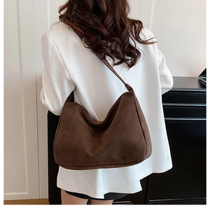Détail du sac hobo en daim marron foncé avec large bandoulière et boucle en métal