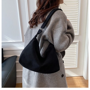 Dettaglio della borsa tote nera in pelle morbida indossata con cappotto grigio invernale