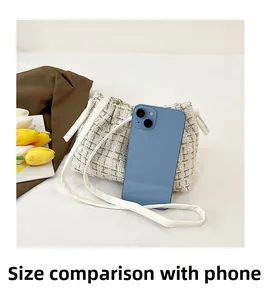 Größenvergleich der Mini-Tweed-Beuteltasche im Verhältnis zu einem Smartphone