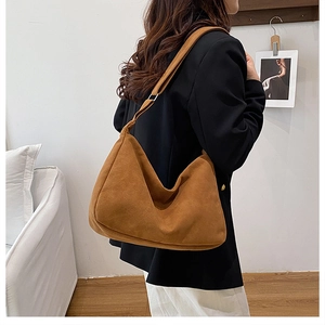 Grand sac hobo marron aspect daim avec large bandoulière porté par un mannequin