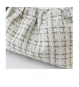 Makroaufnahme der weißen und goldenen Tweed-Stofftextur einer Damen-Umhängetasche